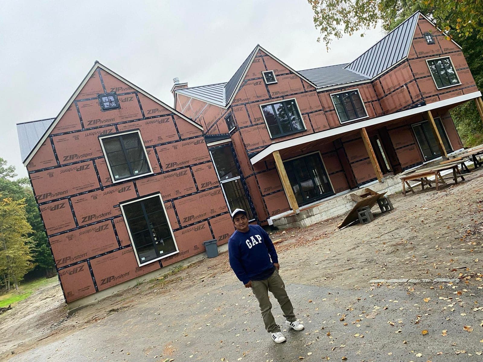 Crew member in front of a home framed with ZIP system sheathing and standing-seam metal roof