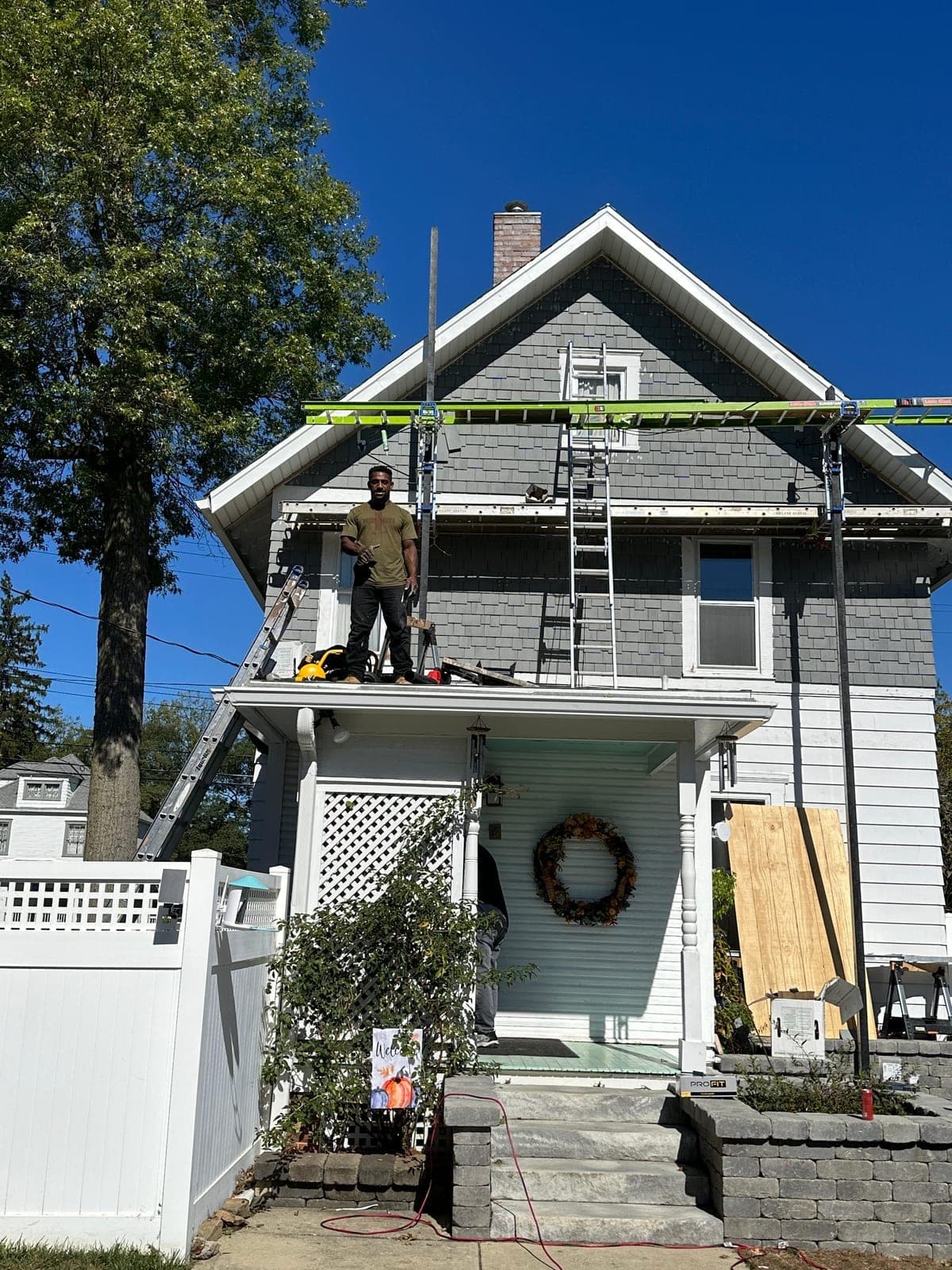 Victorian home with crew member working on the porch roof